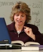 Photo of a student researching with books and a laptop